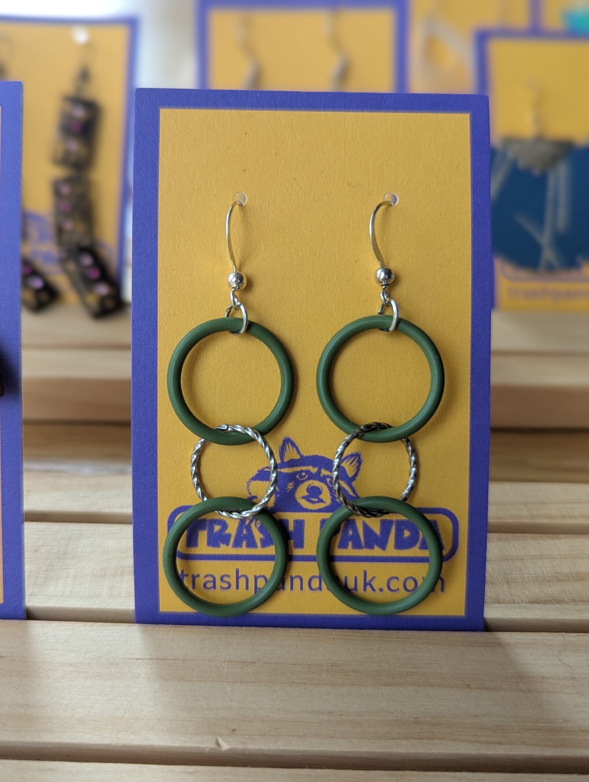 A close up of a pair of earrings on a display card - the earrings consist of three circles of differing sizes, made from rubber and metal