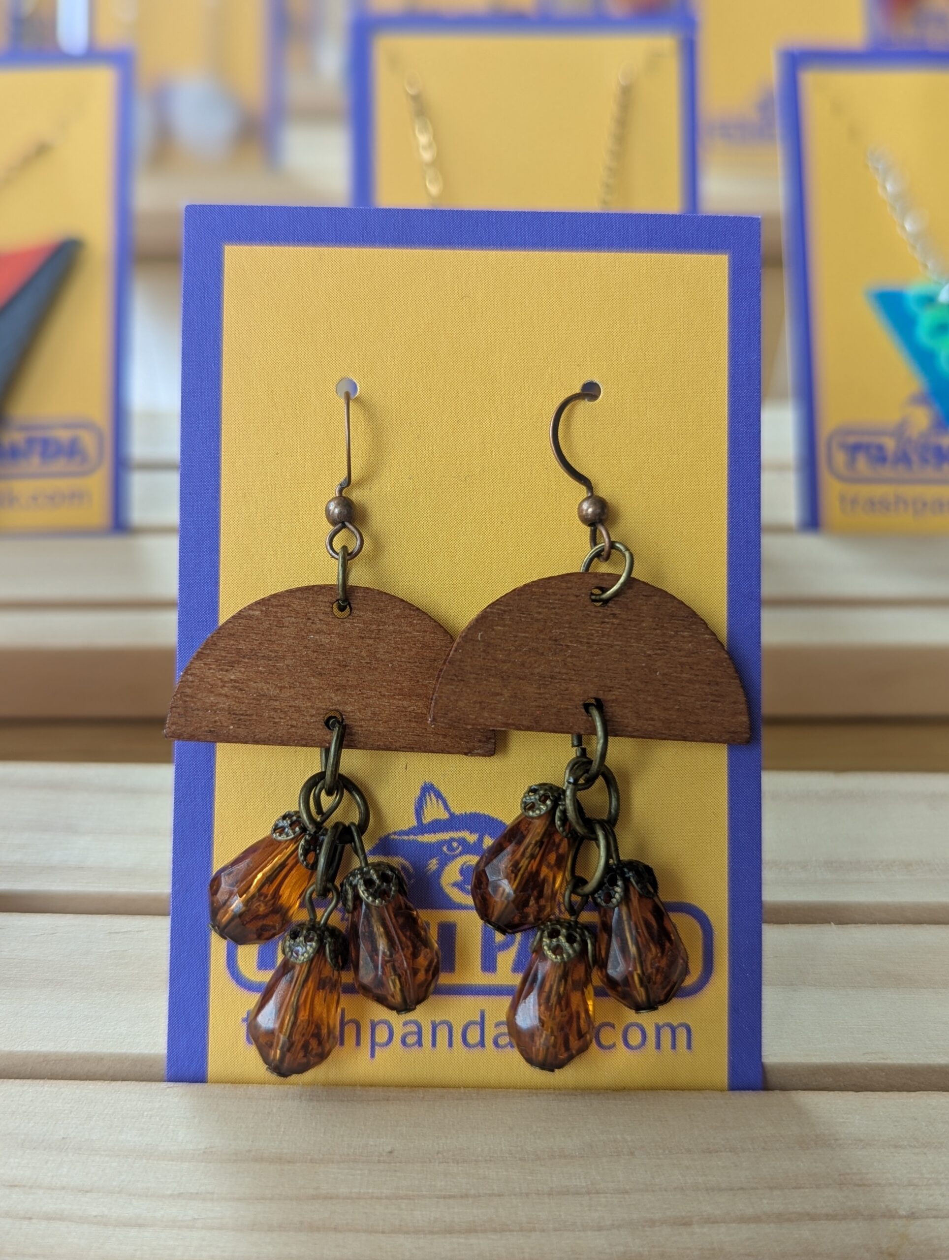 Wood and amber beaded dangly earrings photographed on a jewellery display card
