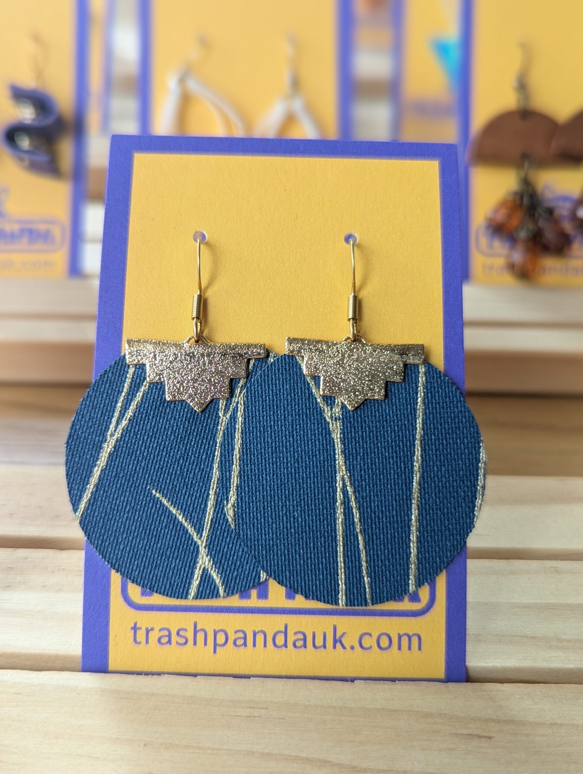Large blue and gold disc earrings on a jewellery display card