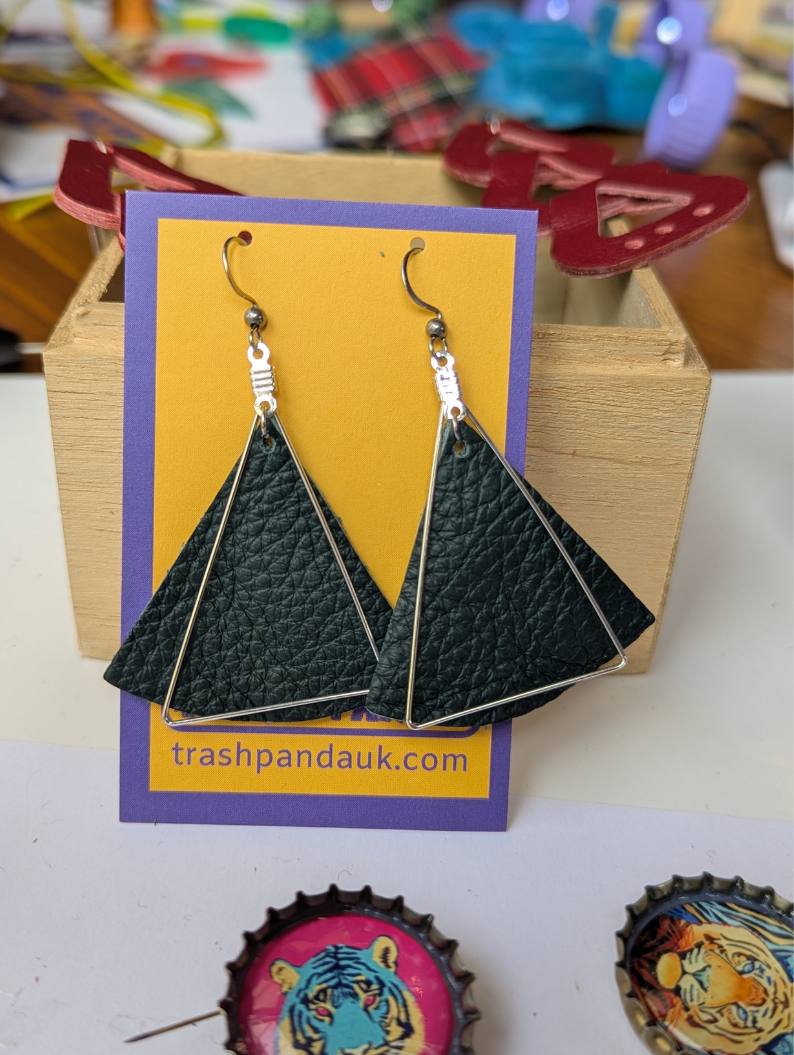 Large dark green leather triangle earrings with silver cut out triangles over top. Displayed on a jewellery card
