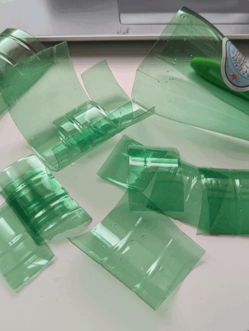 Sparkling plastic water bottles being prepared for upcycled jewellery charms, on a table.