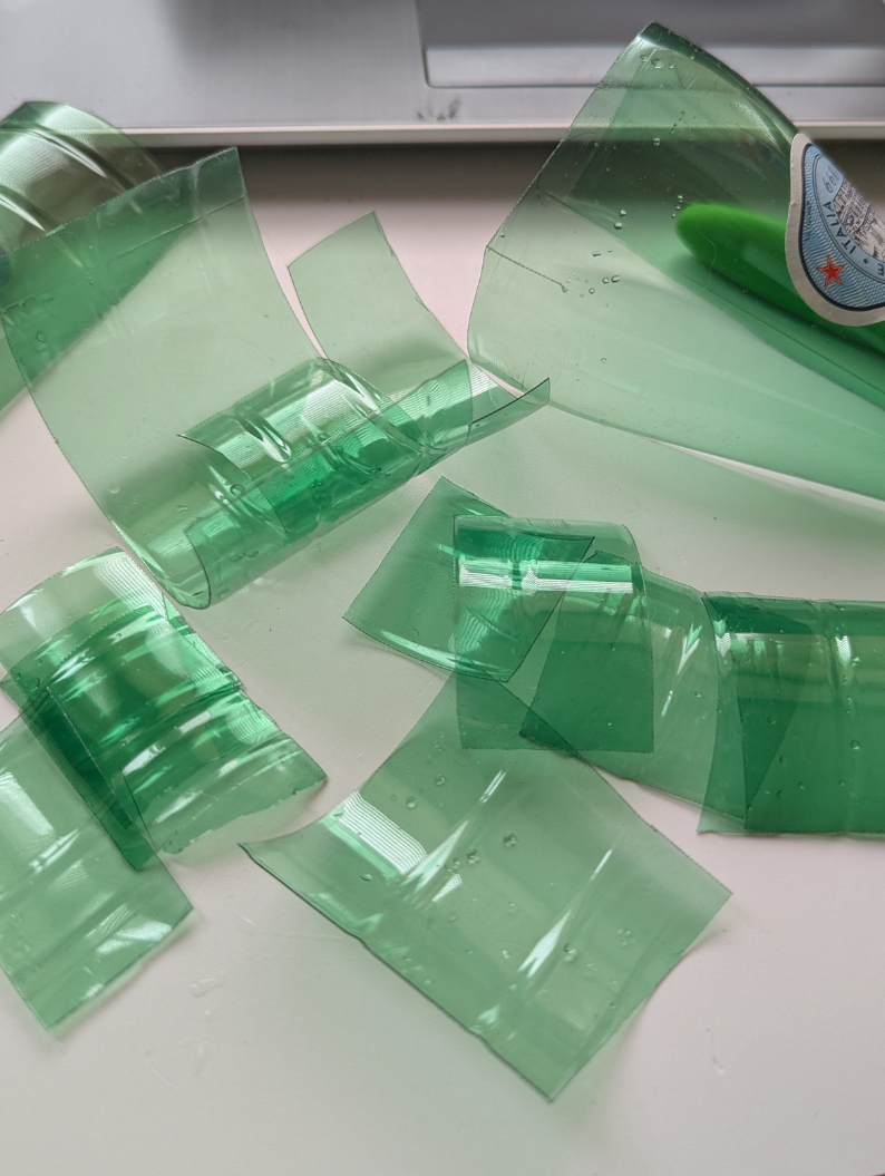 Sparkling plastic water bottles being prepared for upcycled jewellery charms, on a table.