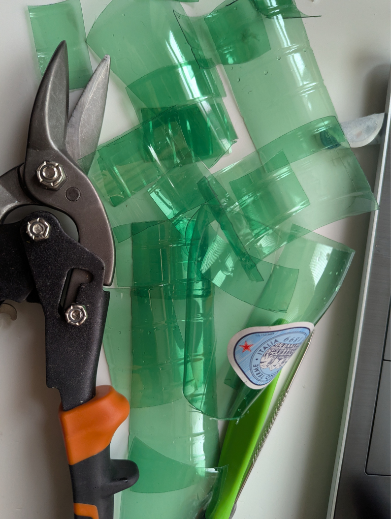 Sparkling plastic water bottles being prepared for upcycled jewellery charms with some tin snips closeby